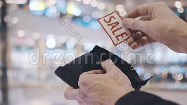 男人的手从空钱包里掏出带有红色<strong>SALE</strong>铭文的斯蒂克。 在黑色星期五之后